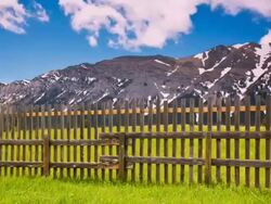Time lapse of clouds moving over mountains and fence Stock Footage