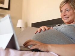 A young women using a technological device while pregnant. Stock Footage