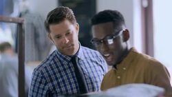 Manager stops to check on shop employee doing inventory with tablet in modern clothing store Stock Footage