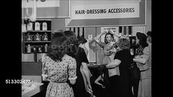 1945: BEAUTY PRODUCTS: HD: Busy city sidewalk. '5 and 10' store sign (five and dime). DRAMATIZATION: Women half-heartedly demonstrating hair curlers in hair-dressing department. Instructional Video
