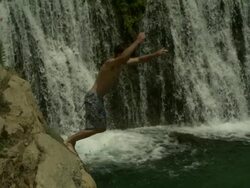 High Speed Man jumping from rocks in to waterfall pool, close up. (Individual frames may also be used as a still image. Each frame in its raw state is about 6MB or about 12MB as a 16 bit TIFF) Stock Footage