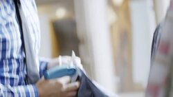 Shop owner prices and tags shirtsleeves with tagging gun in clothing store Stock Footage