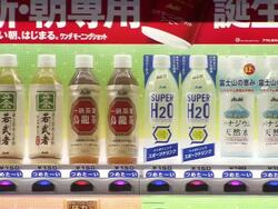 CU Shot of drink vending machine with traffic passing in front of it / Tokyo, Japan Stock Footage