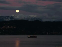 Time lapse of moon rising above harbor and mountain Stock Footage