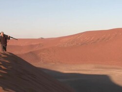 Man with DSLR on tripod walking on sand dune, Sossusvlei, Namib-Naukluft, Namibia Stock Footage