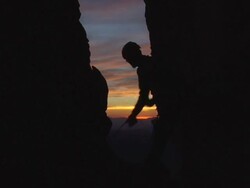 MS Climber pulls up rope  end of  long day of climbing.  Sun setting in background and Climber is silhouetted / Zion, UT, USA Stock Footage