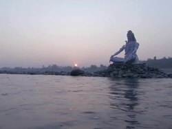 WS POV PAN  White religious statue in mound of rocks in river at sunset / India Stock Footage