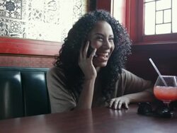 MS Young women talking on cell phone inside restaurant with drink on her table / Minneapolis, Minnesota, United States Stock Footage