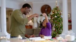 Happy father and daughter sprinkle flour on cookie dough (dolly-shot) Stock Footage
