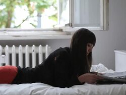 MS Young woman on bed reading magazine by open window / Berlin, Germany Stock Footage