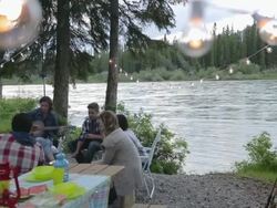 Friends hanging out at riverside campsite Stock Footage