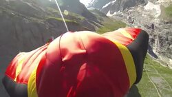 POV wingsuit flying down a cliff face releasing parachute in slow motion Stock Footage