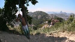 Brazilian boy smiles as he swings standing up overlooking Rio de Janeiro Stock Footage