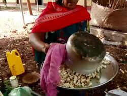 Ethiopian woman serving popcorn onto plate Stock Footage