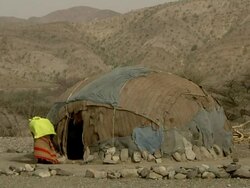 Afar woman and man fixing things around straw hut Stock Footage