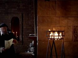 A man near a brick wall reads manuscripts by firelight. Stock Footage