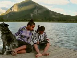 Boom shot of pre-teen girls look at digital tablet, in mtns, with dog Stock Footage