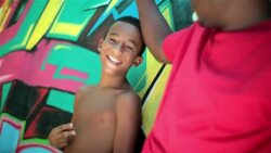 Father puts his arm around son and hugs him leaning on graffitied wall in Rio de Janeiro Stock Footage