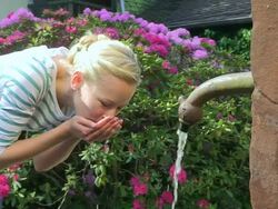 MS Young woman drinking water from well / Saarburg, Rhineland-Palatinate, Germany Stock Footage