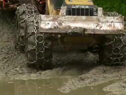 Slight high angle shot of skidder dragging trees, moving through the mud toward the camera. Stock Footage