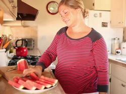 A pregnant women eating and drinking in healthy ways inside of her kitchen. Stock Footage