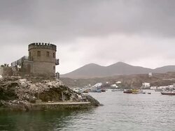 WS View of Brick watchtower at tip of bay, fishing boats moored and Pucusana / Pucusana, Lima, Peru Stock Footage