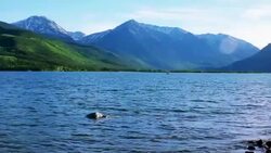 On the edge of Twin Lakes water and waves splashing a lonely boat fishing in the middle of the lake Stock Footage