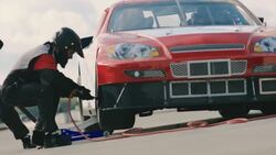 Pit-crew tightens lug-nuts and lowers jack, race-car driver speeds off Stock Footage