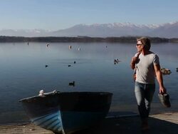 Pan to man walking away from boat, looking back to lake Stock Footage