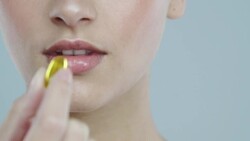 Extreme close-up of young woman with glowing skin taking a vitamin pill Stock Footage