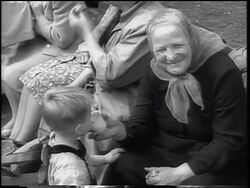 B/W 1961 senior woman holding cup for small boy drinking / East German refugees - Berlin Wall Stock Footage