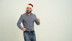 young adult beard man dancing in a hat santa claus on a grey background Stock Footage
