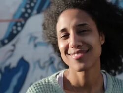 Young woman with curly hair looking into camera, smiling, laughing in sunshine Stock Footage