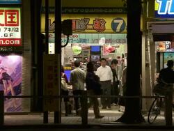 MS Shot of manga comic shop in Tokyo with pedestrians and traffic passing in front of it at night / Tokyo, Japan Stock Footage