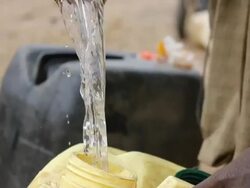 Pouring water into canister with a calabash Stock Footage