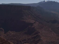Long Shot aerial tracking-left - A paraglider sails past  rock formations in a desert / Egypt Stock Footage