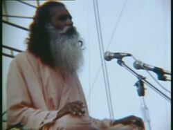 1969 MONTAGE MS ZO ZI Indian Guru figure sitting onstage, speaking and singing at the opening of Woodstock music festival Stock Footage