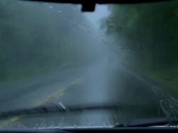 Medium shot car point of view driving along rainy highway / windshield wipers wiping away rain Stock Footage