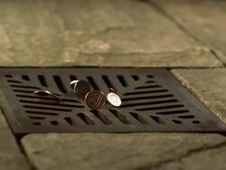 Money Down the Drain - High speed various English coins falling on and in to road drain, wide Stock Footage