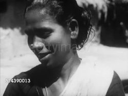 1949: INDIA CASTE SYSTEM: OUTCASTS / UNTOUCHABLES: VS Small group of women washing pots in shade at village well. VS Mother holding child at market while food shopping, female merchant weighing potatoes, into woman's basket, woman watching, leaving. Instructional Video