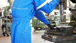 Worker in protective suit working in factory on machinery Stock Footage