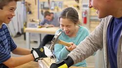 Elementary age Hispanic girl hammers a nail into a board in community workshop day camp Stock Footage