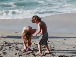 MS TS Girl tries to put two water balloons in bikini and boy steals one away to hold up to his chest as they fight over one water balloon on beach with ocean and man / Montezuma, Puntarenas, Costa Rica Stock Footage