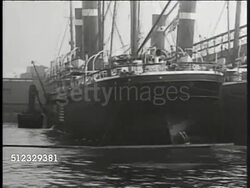 1917: EXECUTIVE ORDER TO ARM SHIPS: American US flag painted on side of Merchant ship. PAN Harbor w/ ships docked. MS (Side) President Woodrow Wilson sitting at desk, writing on bottom of paper (not just signing). Instructional Video