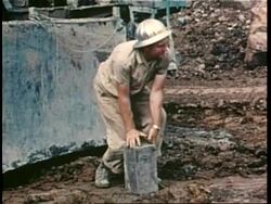 A demolition worker depresses a dynamite plunger. News Clip
