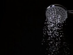 CU LA SLO MO Shot of shower spraying water out against black background / Calvados, Normandy, France Stock Footage