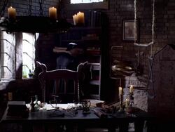 A man in period clothing places an item on a bookshelf near a chandelier of burning candles. Stock Footage