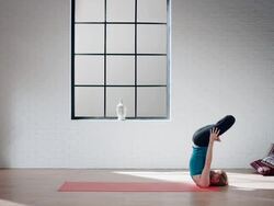 Woman practicing yoga in gym (full shoulder stand in lotus) Stock Footage