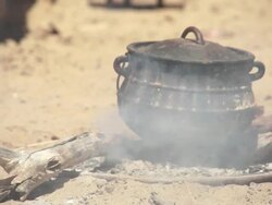 CU Cast iron pot is cooking on pile of ashes and coals in himba village / Himba, Kunene, Namibia Stock Footage