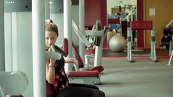 Woman sitting down at shoulder press exercise machine at gym Stock Footage
